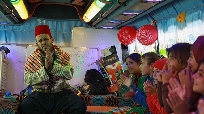 أطفال سوريون نازحون يغنون في حافلة تم تحويلها إلى فصل دراسي